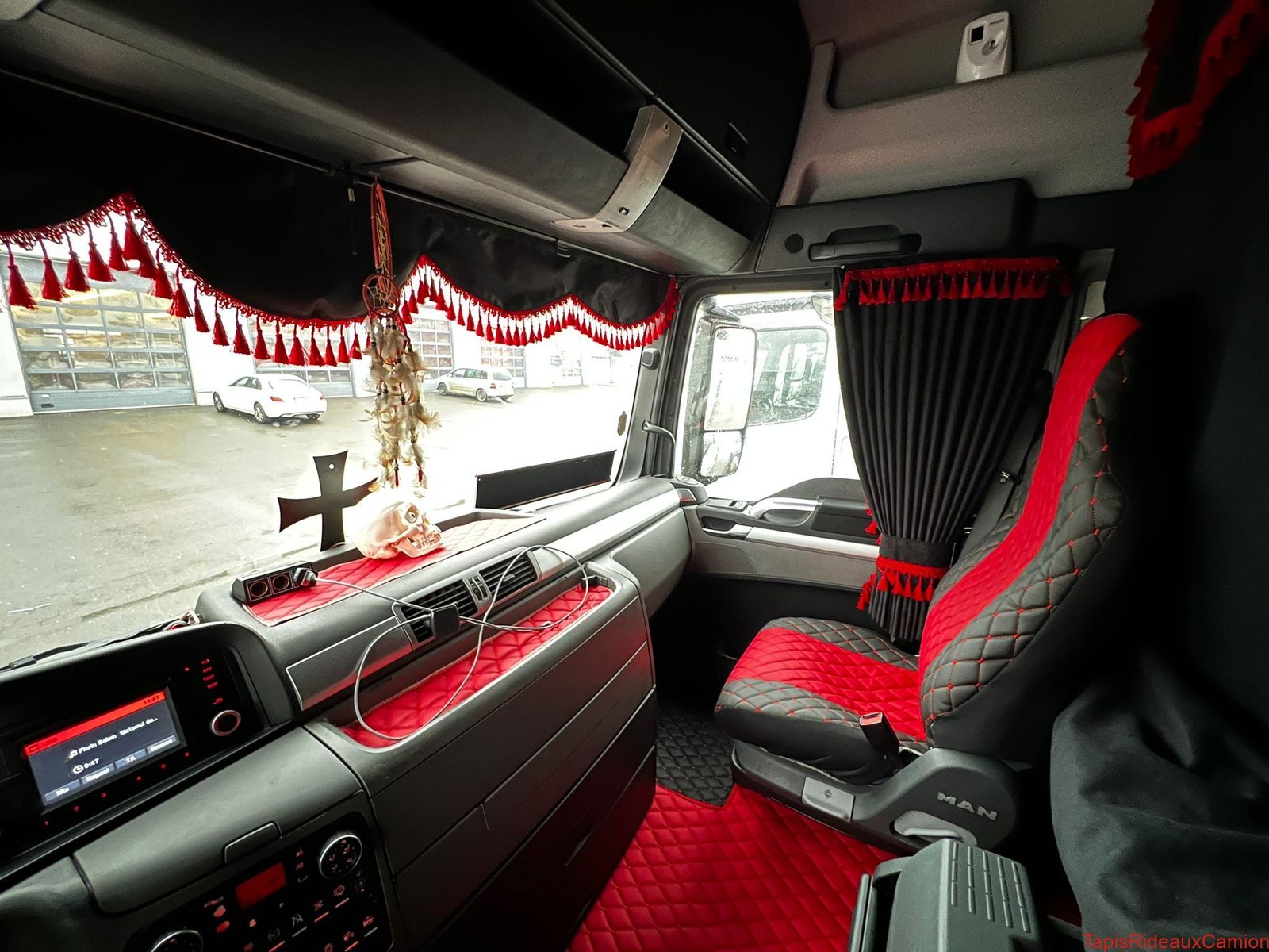 Frange de pare-brise en alcantara noire avec des pompons rouges, housses de sièges en similicuir noire et rouge, tapis de sol en similicuir noire et rouge, rideaux en alcantara noire avec des pompons rouges pour camion MAN TGX sur mesure